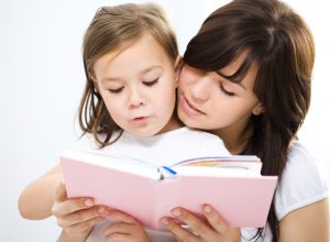 Mother is reading book with her daughter, indoor shoot